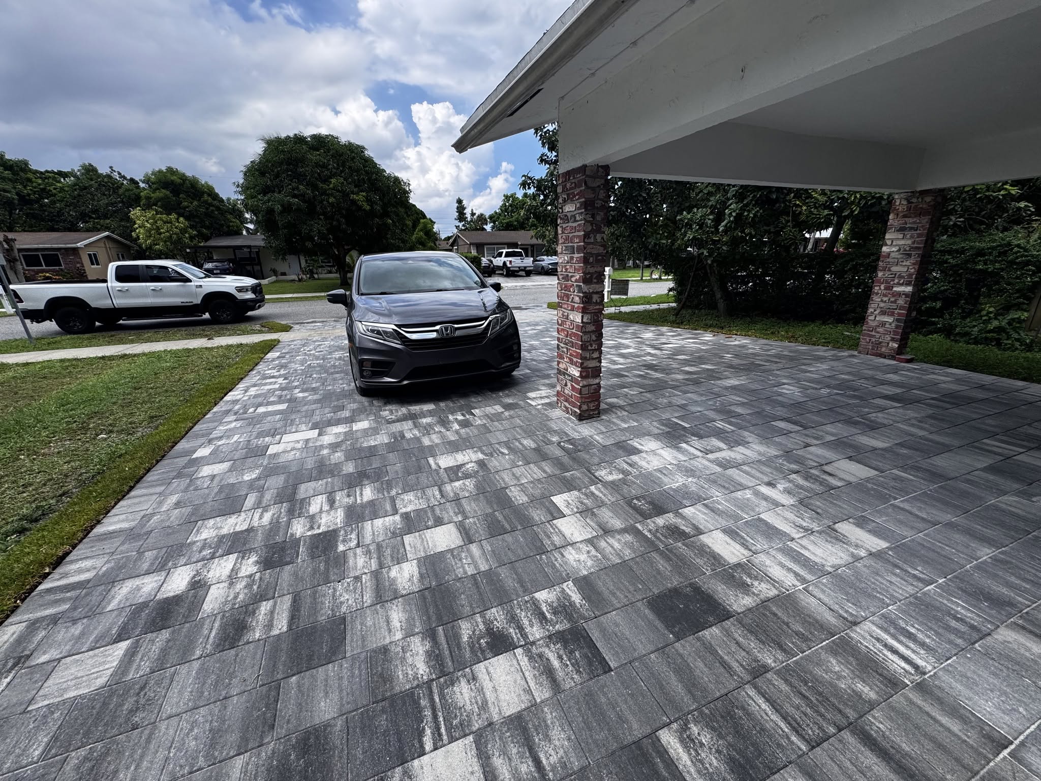 Glacier Ultra Combo pavers connect the widened driveway and carport. Pavers outside the carport are damp from rain, while the covered area is dry.