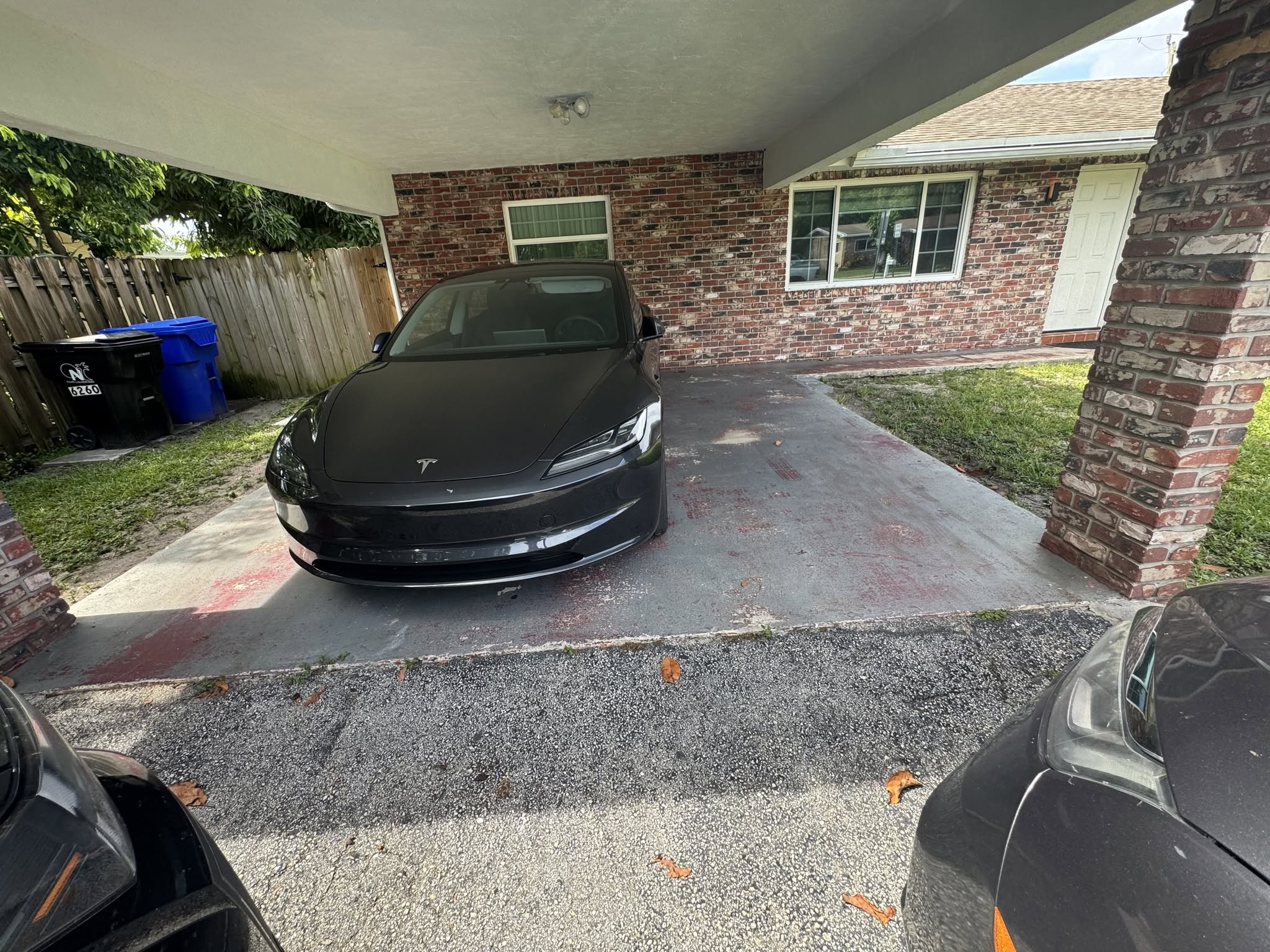 The original carport surface with peeling finish, adjoining the old asphalt driveway.